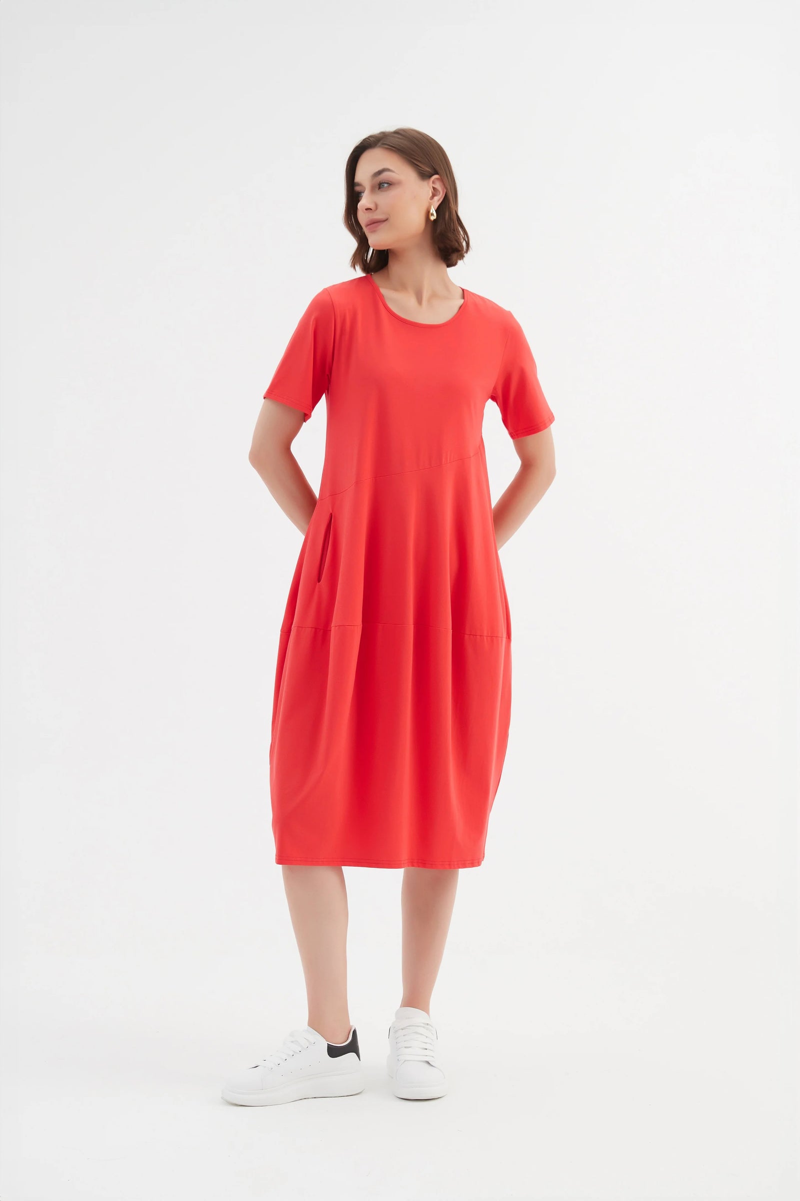 Model wearing midi dress in red with short sleeves, pockets and balloon skirt by Tirelli.