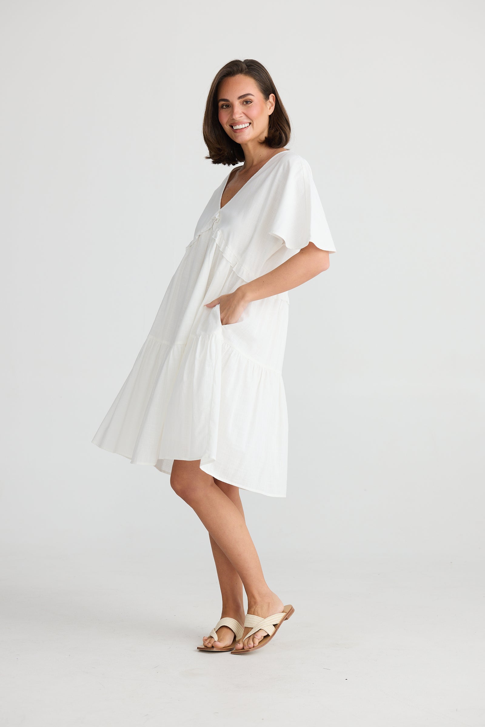 Side of knee length white v-neck tiered Lola midi dress by Holiday.