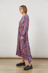 Side view of Floral Romance Maxi Dress with V-Neck and self tie, wide ruched waist band and Wide ruffle along hem