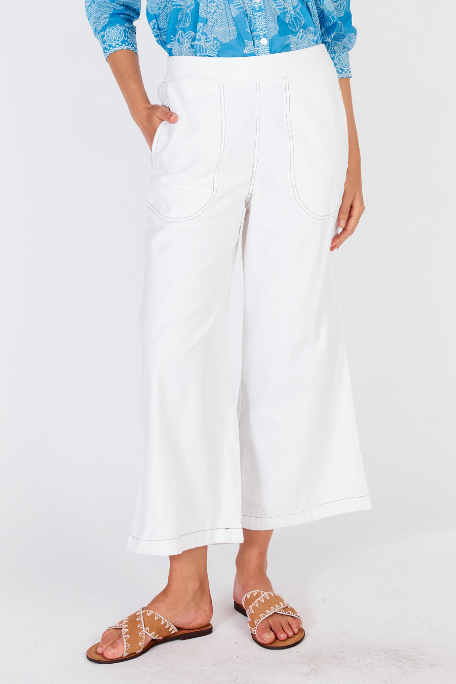 Woman wearing white cotton Pula pants from Rubyyaya with a slight crop above ankles.