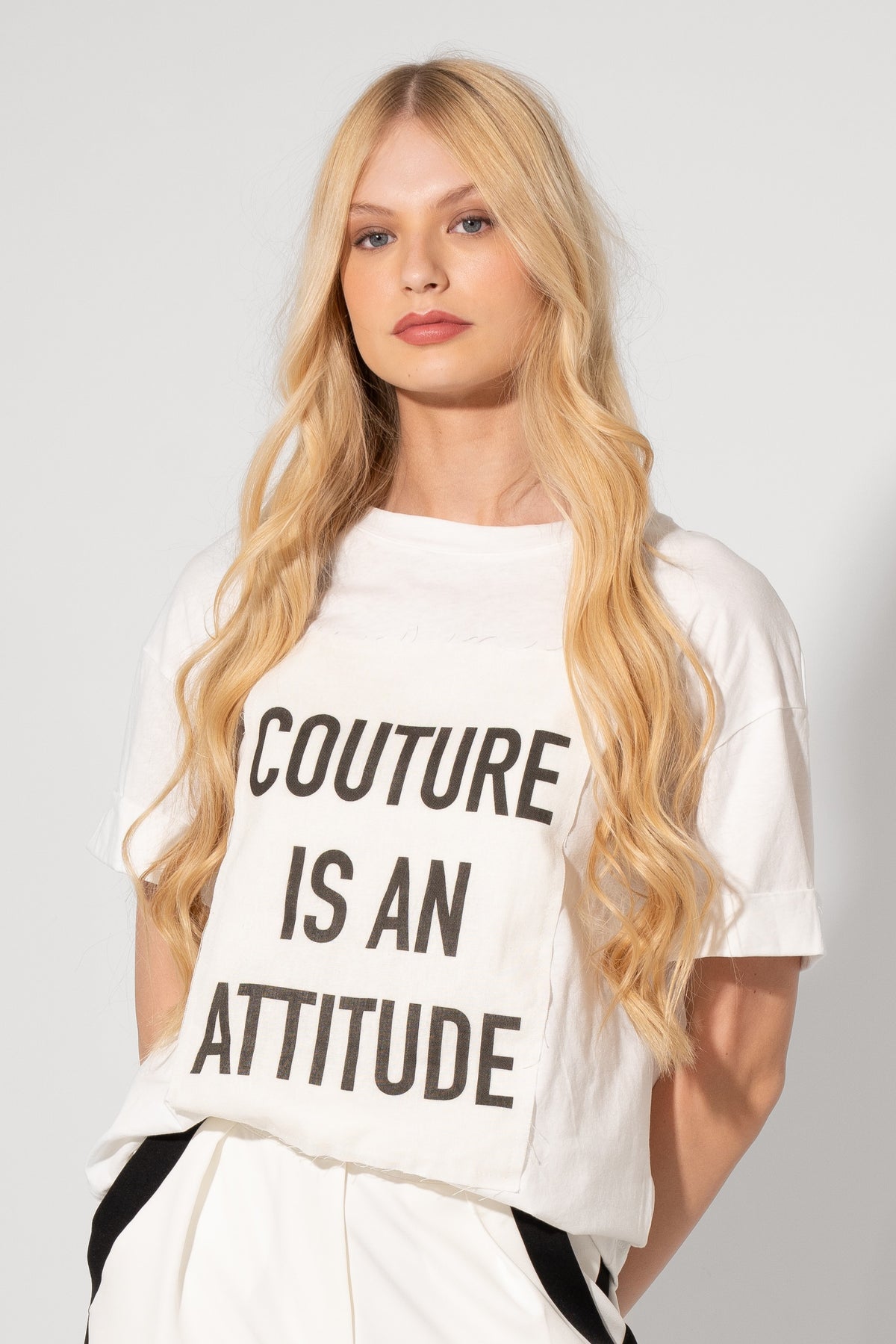 Woman wearing a white t-shirt with &#39;Couture is an attitude&#39; text with short sleeves by Astrid.
