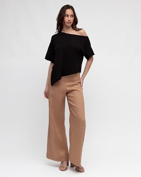 Woman wearing the Asy Knit Off Shoulder Black Top by White Closet with a pointed hemline and short sleeves.