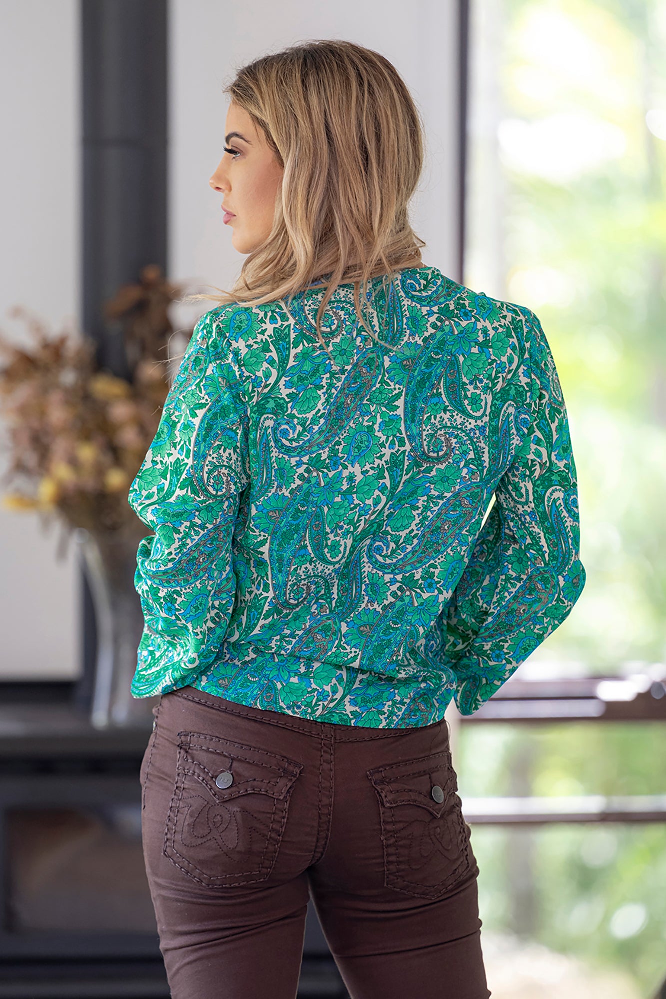 Lady wearing the stunning silk blend Beatrix crossover top by Cienna in a green and blue paisley print with long sleeves and a v-neck.
