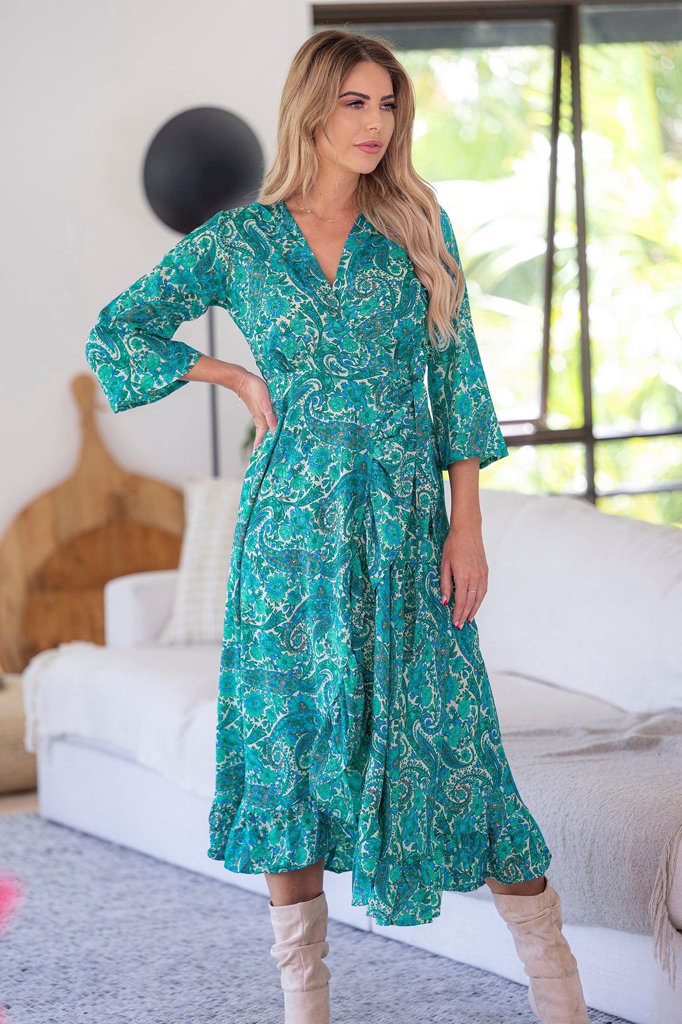 lady wearing Cienna's Beatrix silk blend boho wrap midi dress in green, blue and white paisley print with long sleeves and a ruffle hem. 