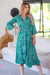 lady wearing Cienna's Beatrix silk blend boho wrap midi dress in green, blue and white paisley print with long sleeves and a ruffle hem. 