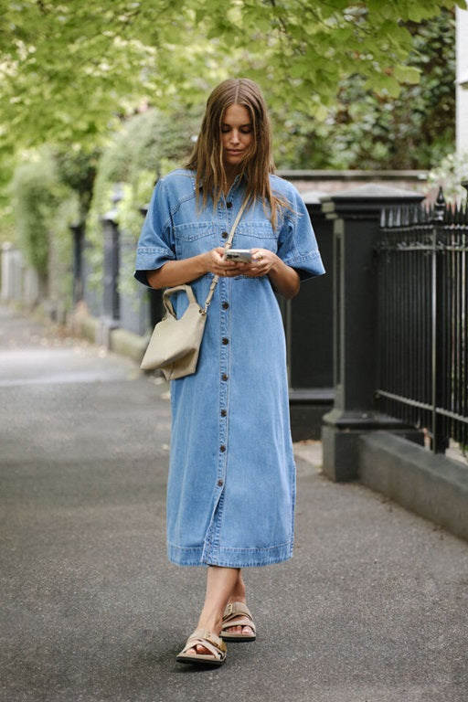 Model wearing Ava Short Sleeve Yoke Detail Midi Denim Dress in Vintage Blue with Button Front and pockets by Ceres Life.