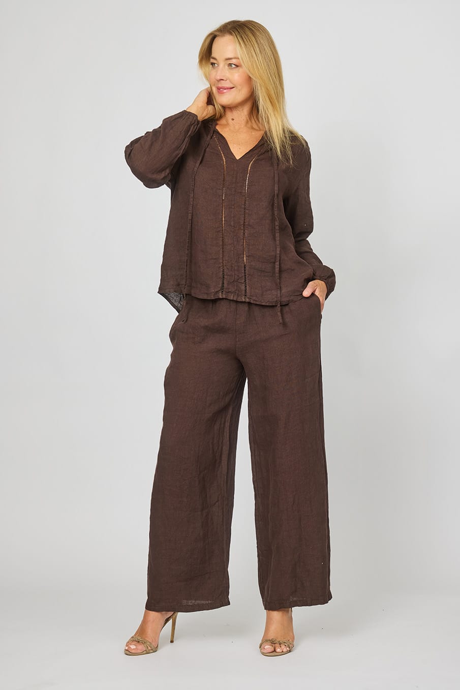 Woman wearing Long Sleeve Linen Top in Chocolate wtih eyelet broderie embroidery down the front, v-neck and ties by La Strada.
