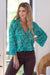 Lady wearing the stunning silk blend Beatrix crossover top by Cienna in a green and blue paisley print with long sleeves and a v-neck.