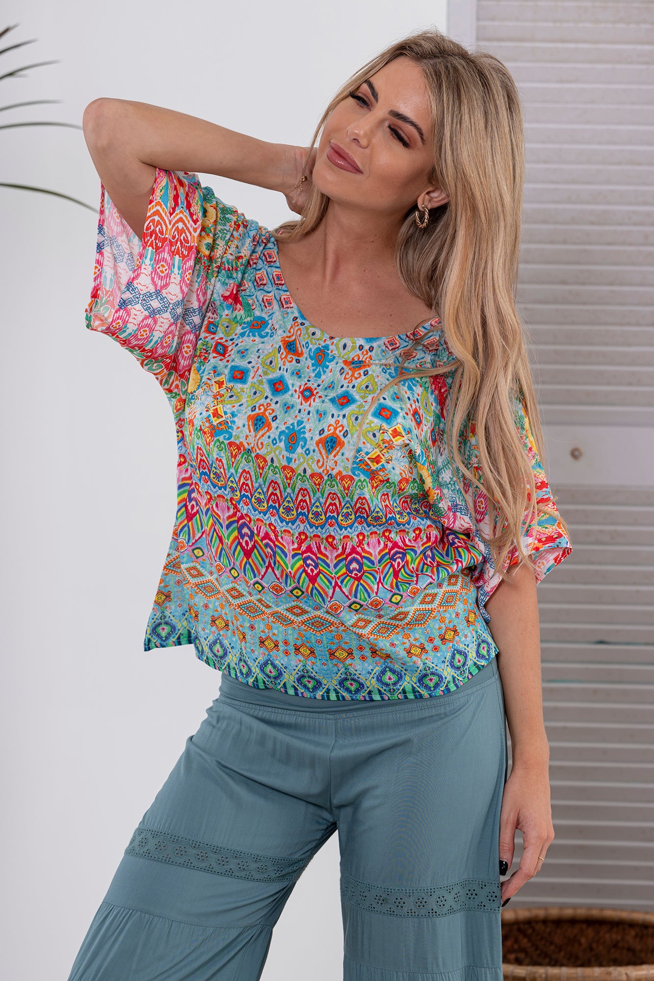 Woman wearing Cienna's bright geometric Carmen Blouse Top in Multi with short sleeves and a round neck.
