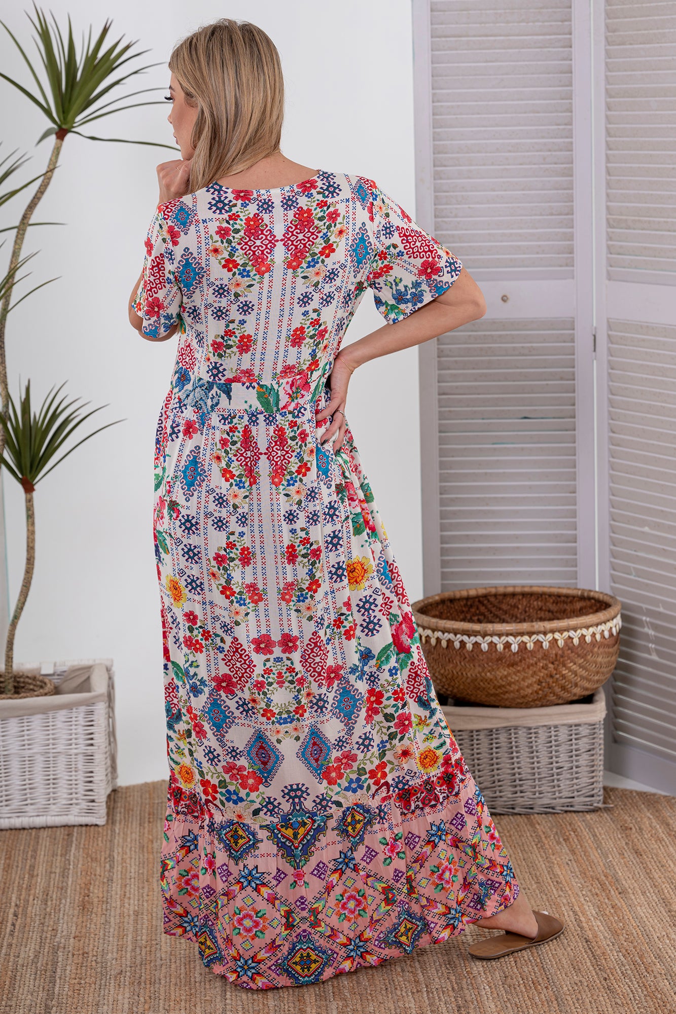 Woman wearing Cienna's cross stitch print maxi dress in white, blue red and pink with short sleeves and a v-neck.