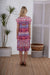 Lady wearing Cienna's SIgrid Midi Dress in Blue, white red and pink with cap sleeves and a gathered tiered hem with eyelet embroidery.
