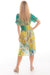 Model wearing Cienna's silk blend Vera Midi dress in green and yellow floral boho print with a v-neck, short sleeves and wide shirred waist.