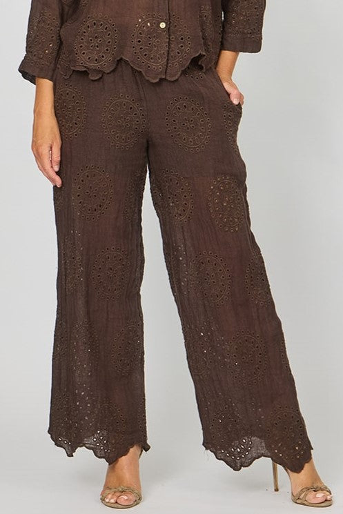 Woman wearing the eyelet embroidery broderie anglaise brown linen pants by la Strada.