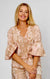 Woman wearing puff sleeve cotton top in pink, brown, beige and white pretty floral print, with short sleeves and a v-neck by La Strada.