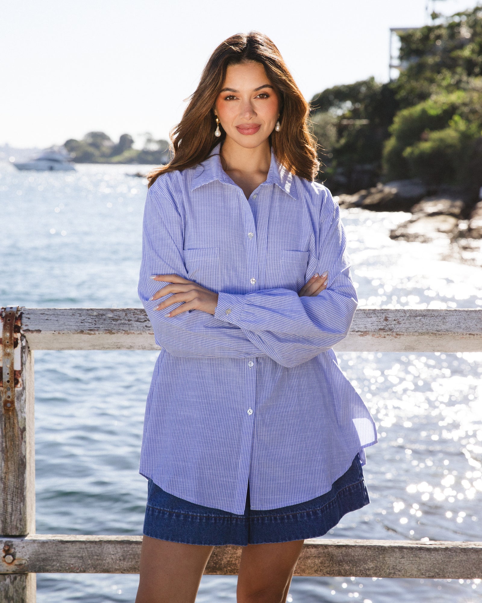 Woman wearing Marina striped shirt in pink and white thin stripes with collar and button up front with long sleeves with cuff by Label of Love.