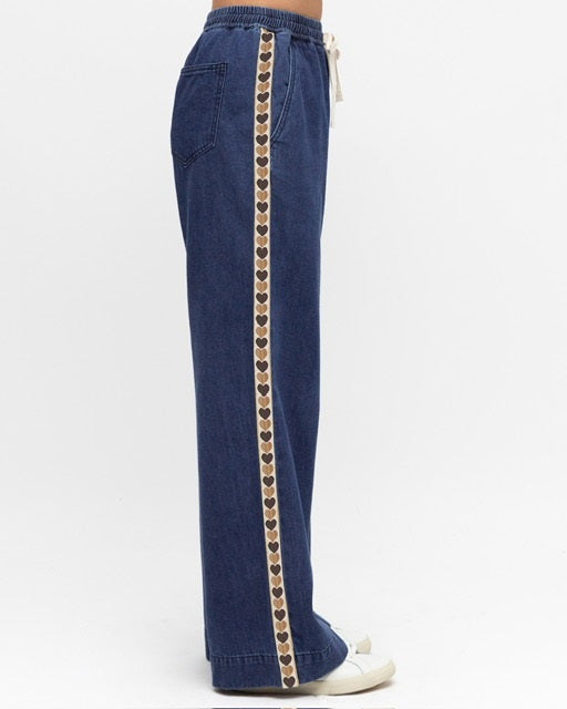Woman wearing Label of Loves Side Stripe jeans with Love Hearts, pockets, elasticated waist and full length in a mid denim blue.