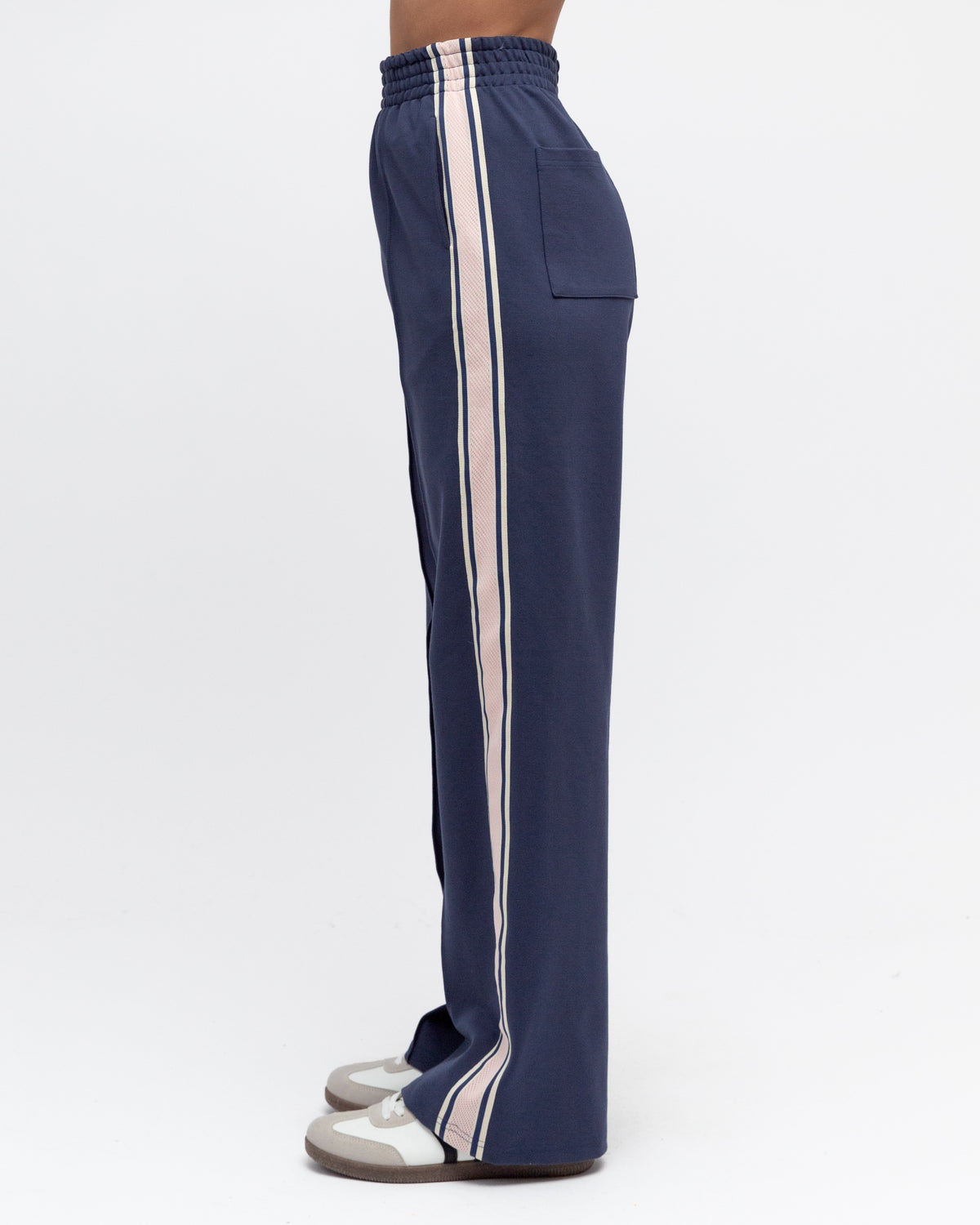 Navy blue track pants with white stripes on a white background