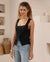 Woman wearing a square neck, black sleeveless tank top with wide straps and a split at the front.