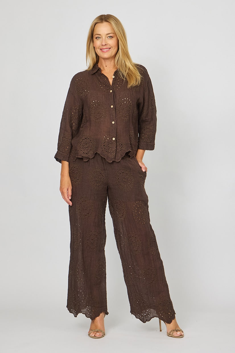 Woman wearing the eyelet embroidery broderie anglaise brown linen pants by la Strada.