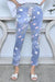 Lady wearing Cali&Co's rib waist stretch floral pants in denim blue (pale) floral print (in white and pink).