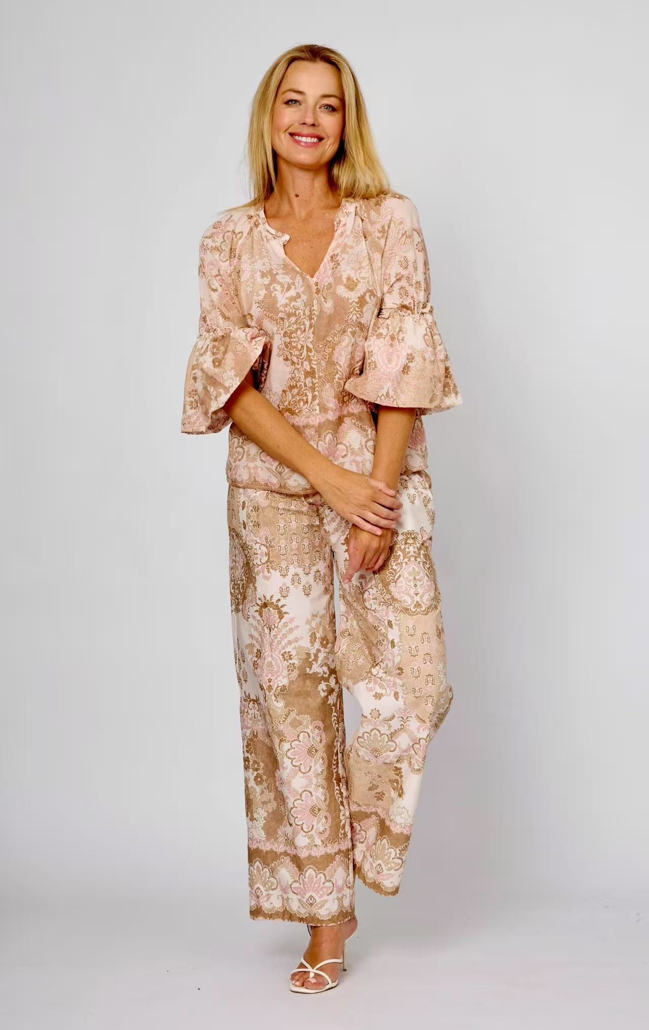 Woman wearing puff sleeve cotton top in pink, brown, beige and white pretty floral print, with short sleeves and a v-neck by La Strada.