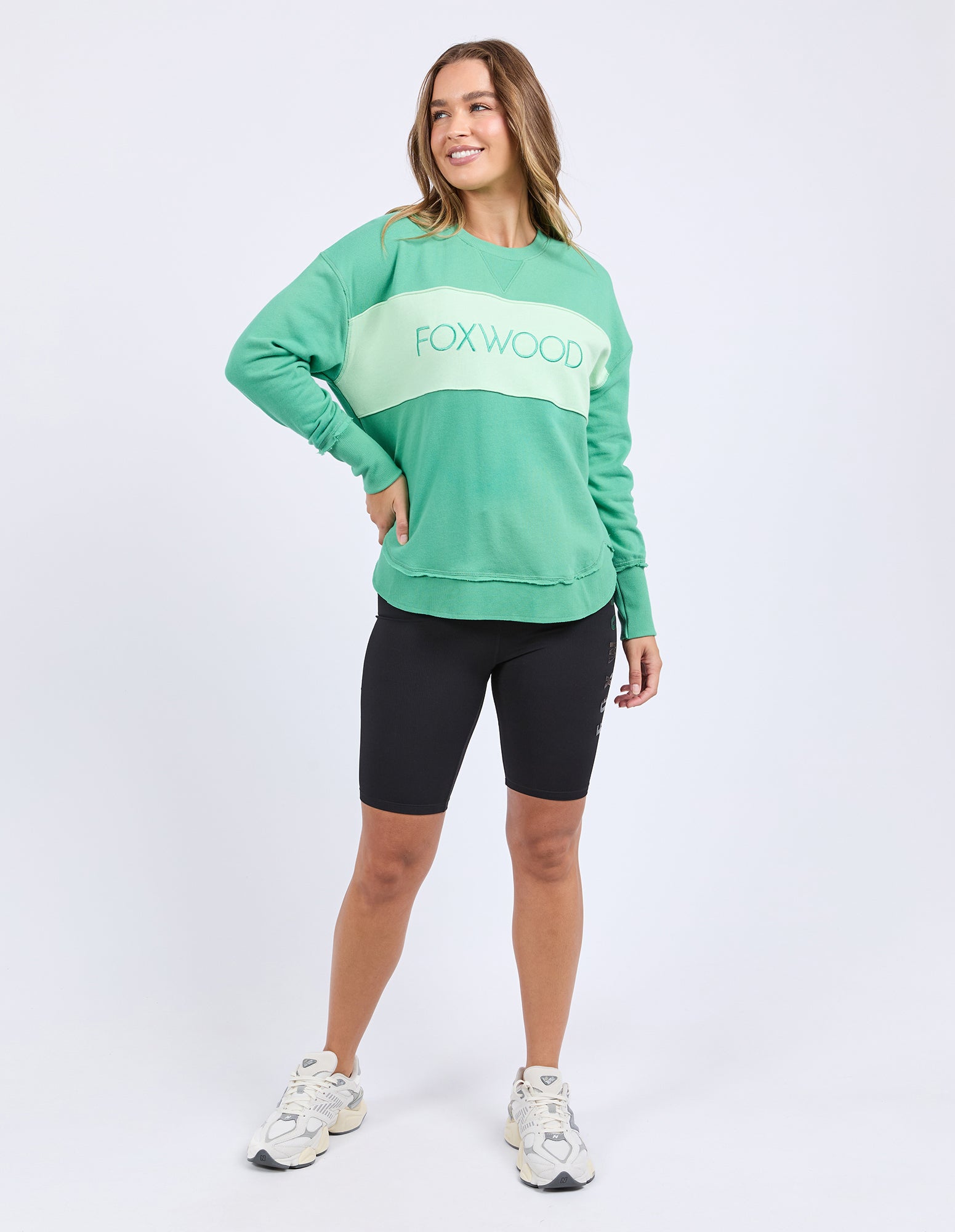Woman wearing a green cotton tonal crew sweatshirt with 'FOXWOOD' logo on front.