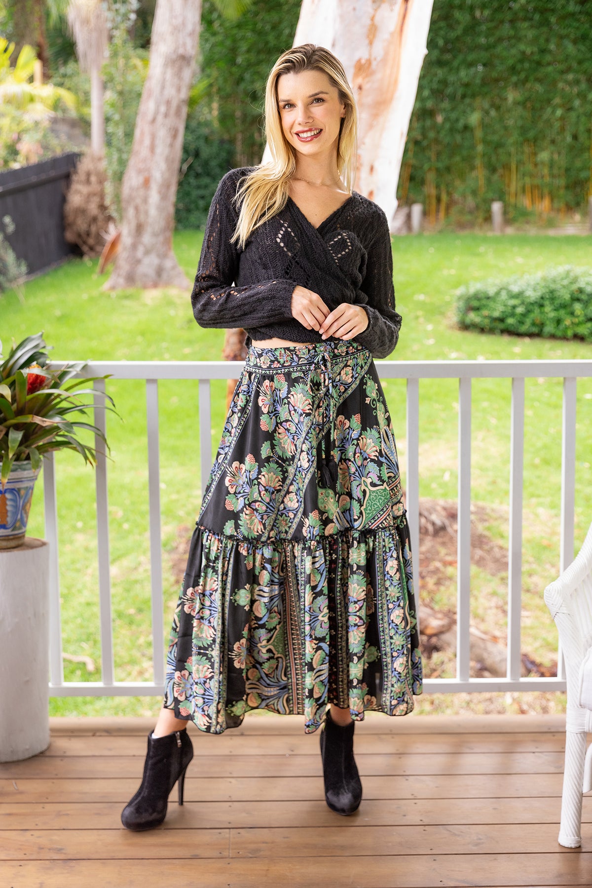 Woman wearing Cienna&#39;s Myra Boho Tiered Maxi Skirt in Black Floral Multi with tie waist.