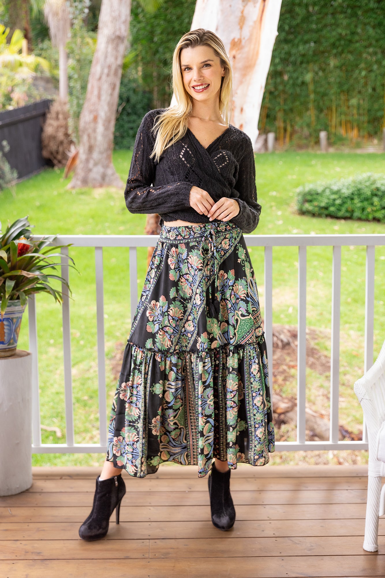 Woman wearing Cienna's Myra Boho Tiered Maxi Skirt in Black Floral Multi with tie waist.