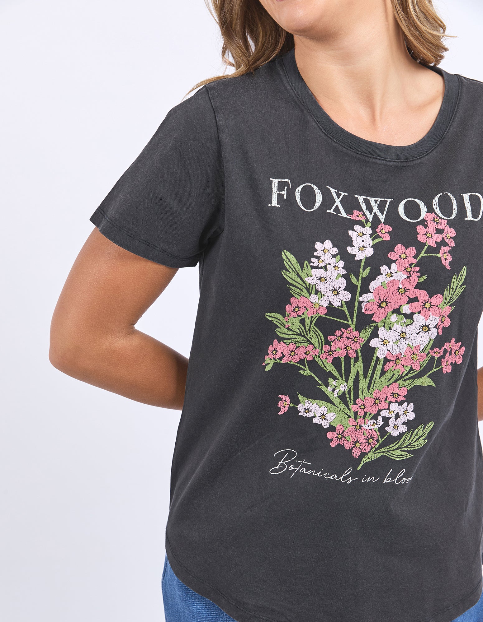 Woman wearing a washed black Flowers Tee with short sleeves, round neck, curved hem T-shirt from Foxwood.