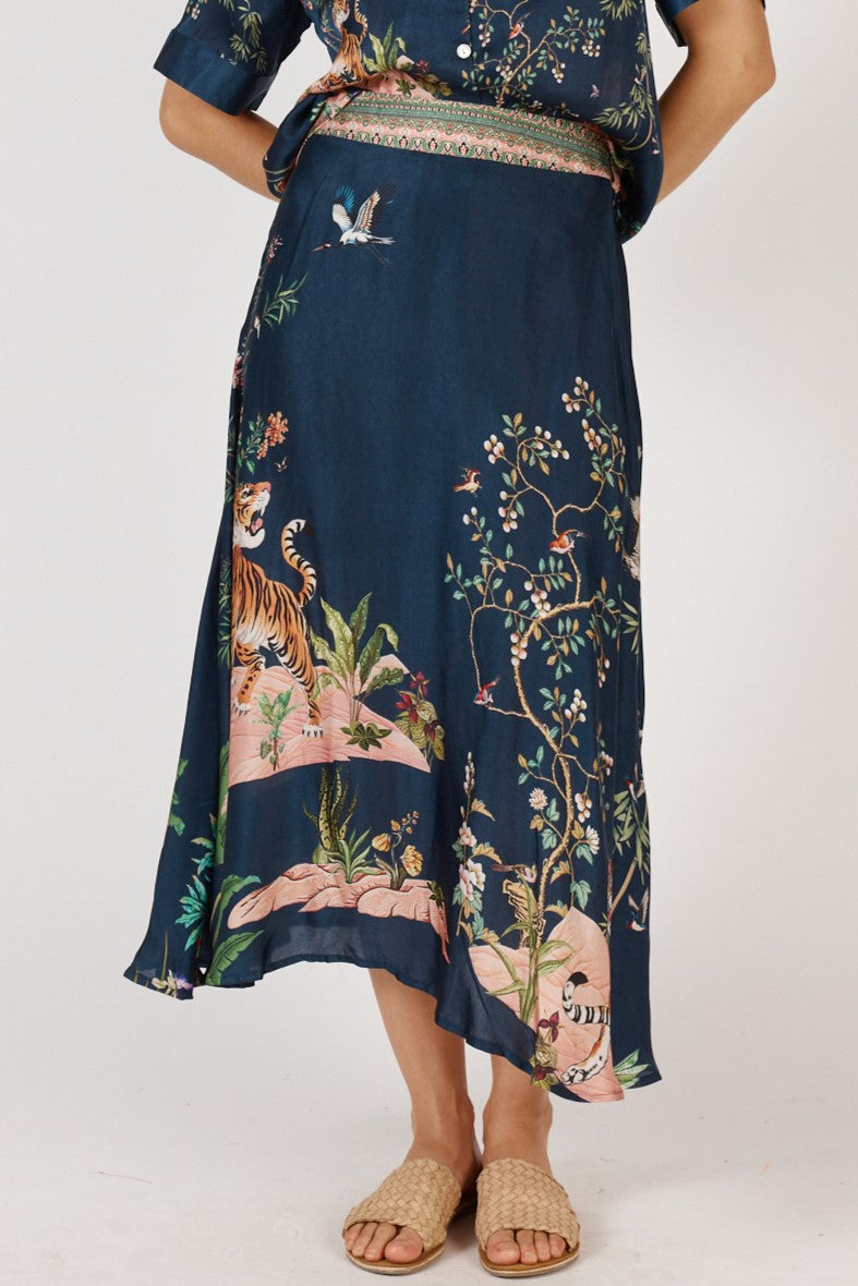 Woman wearing blue satin midi skirt with tigers and jungle print by Rubyyaya.
