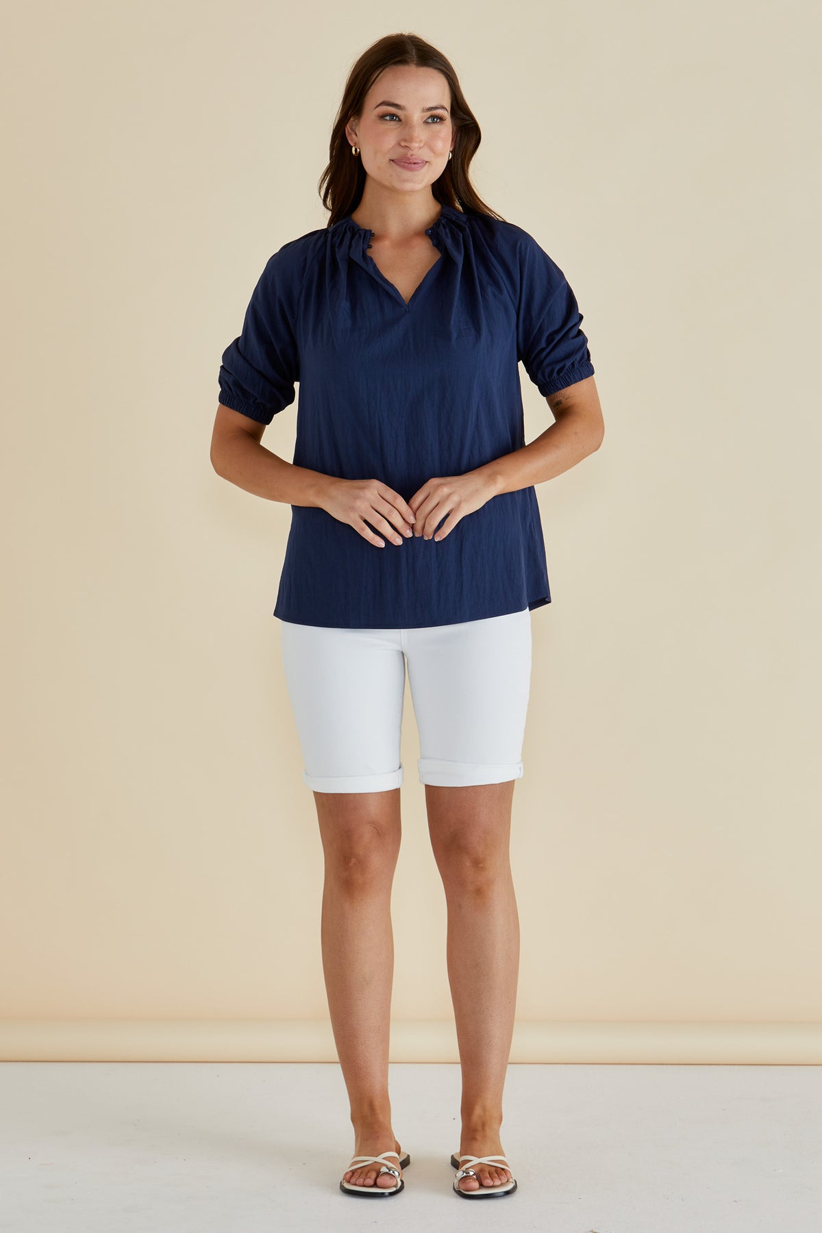 Woman wearing the Navy Blue Joanne Blouse Top with Short Balloon Sleeves, a v-neck and straight hem by Betty Basics.