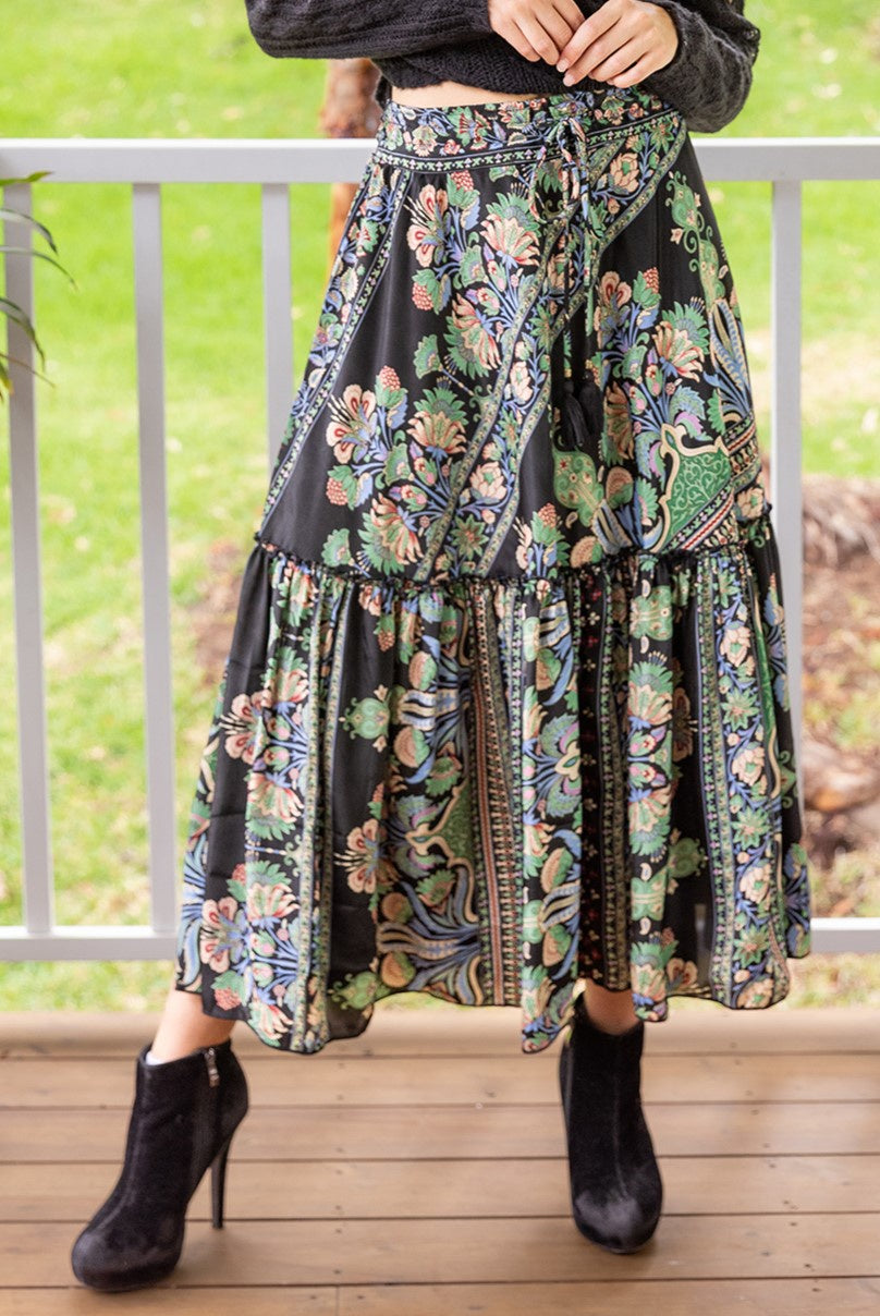 Woman wearing Cienna's Myra Boho Tiered Maxi Skirt in Black Floral Multi with tie waist.