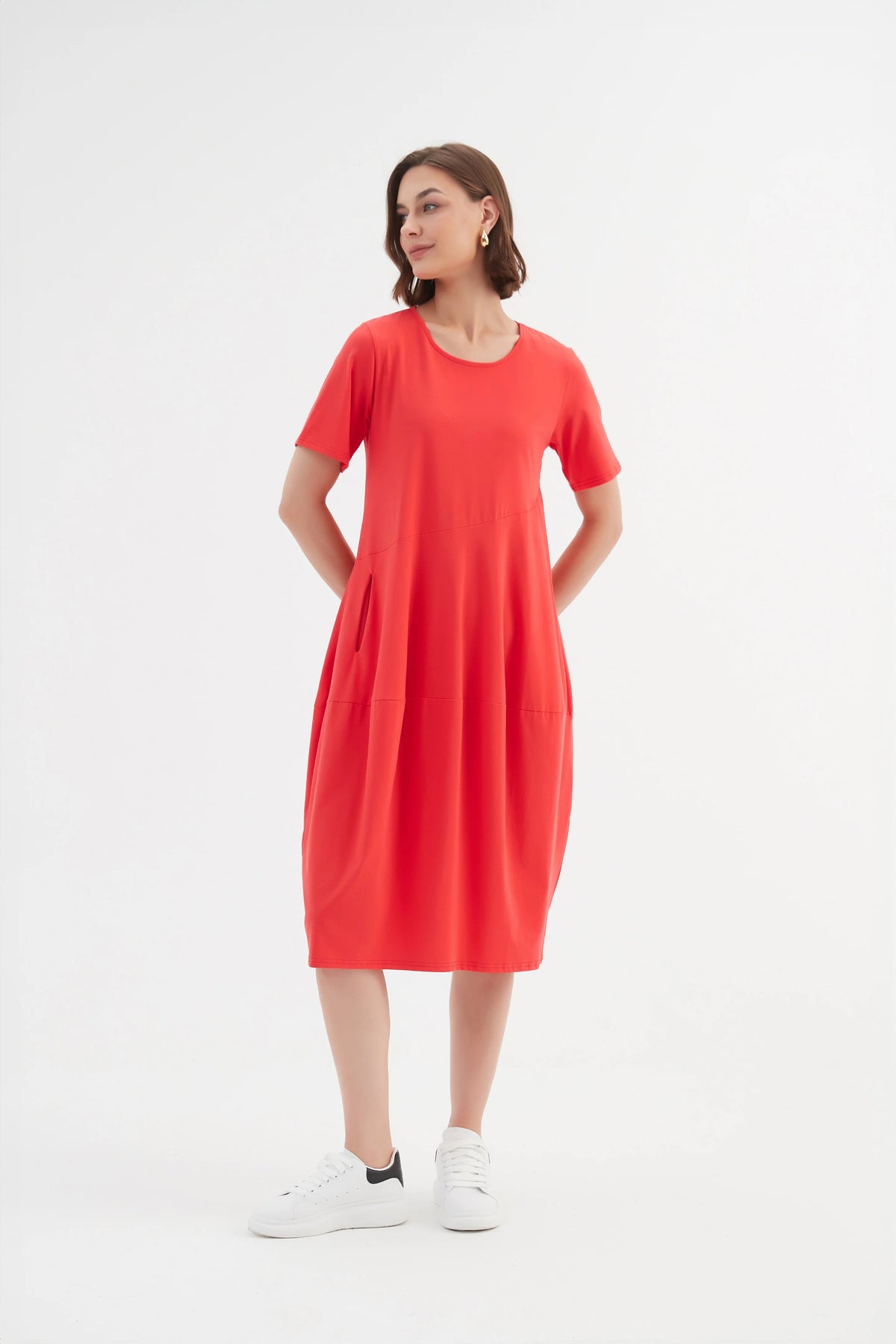 Model wearing midi dress in red with short sleeves, pockets and balloon skirt by Tirelli.