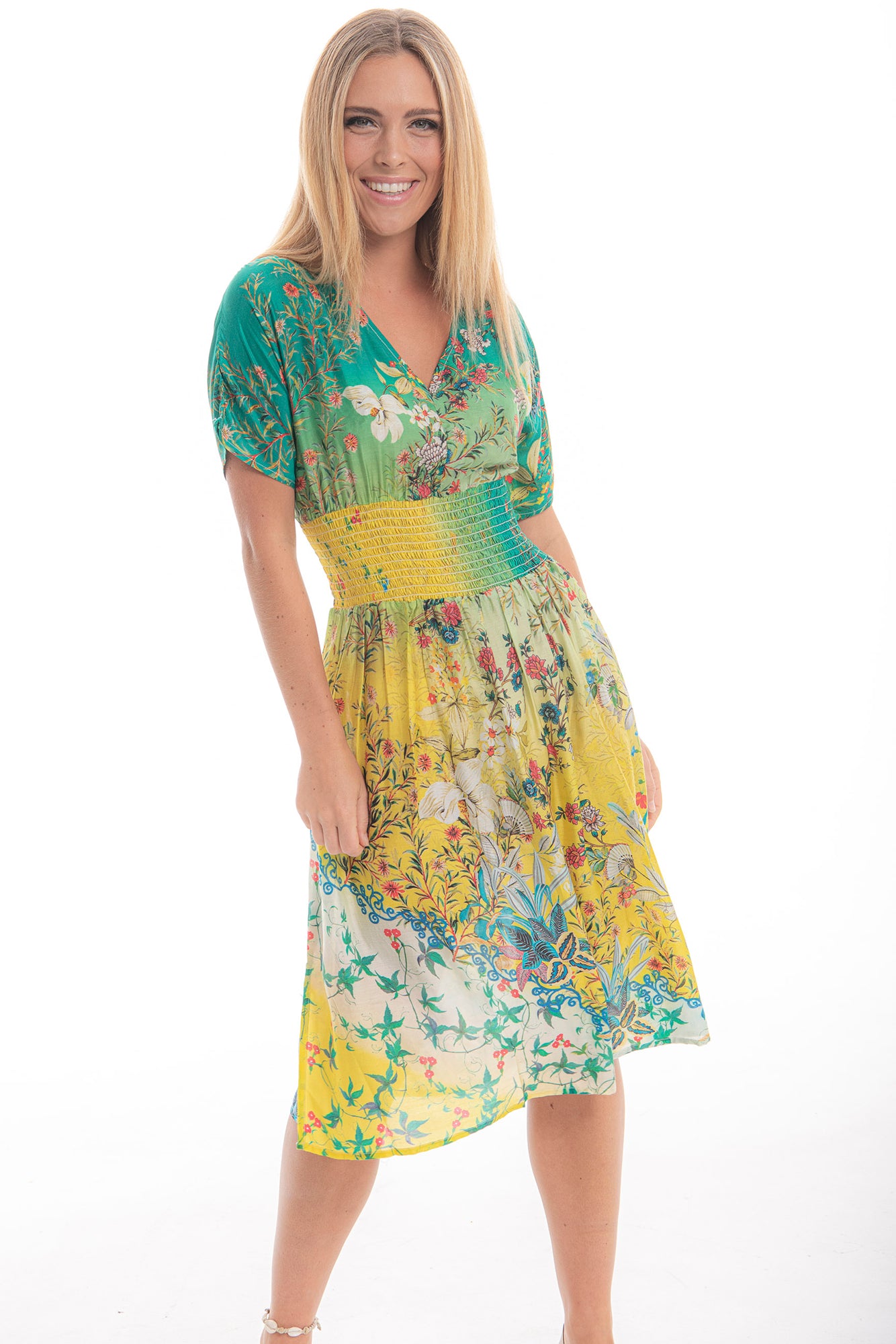 Model wearing Cienna's silk blend Vera Midi dress in green and yellow floral boho print with a v-neck, short sleeves and wide shirred waist.